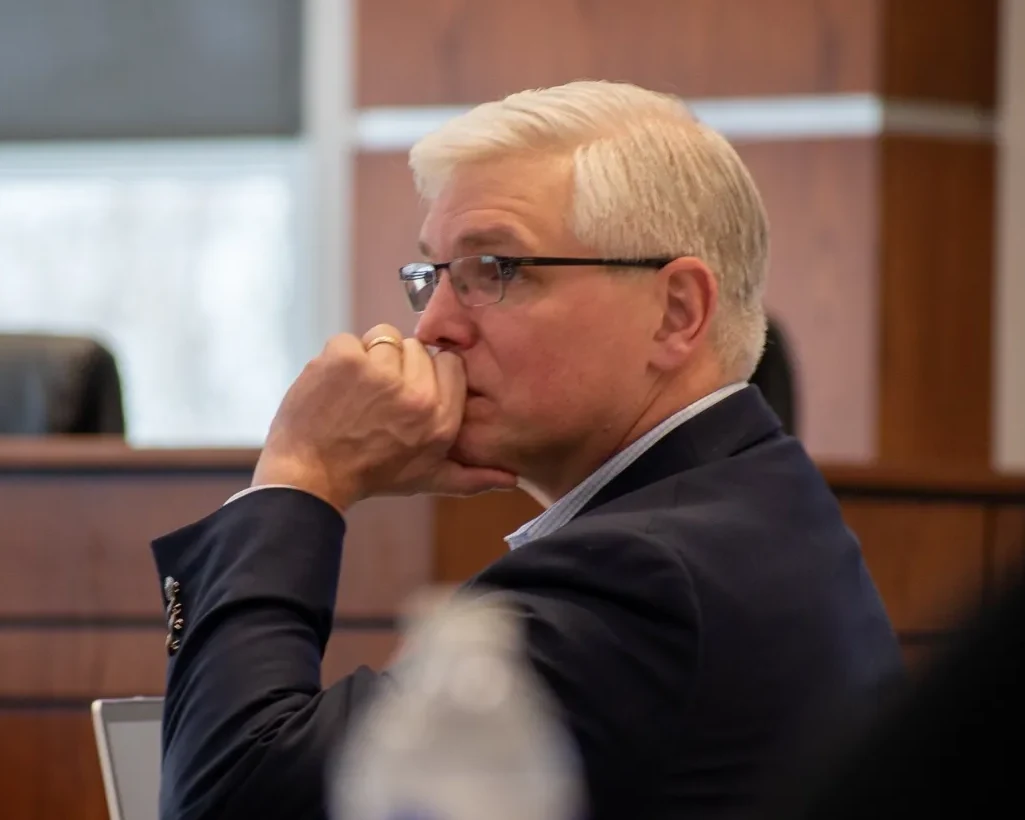 Andrew Flynn listening from the dais during a public meeting.